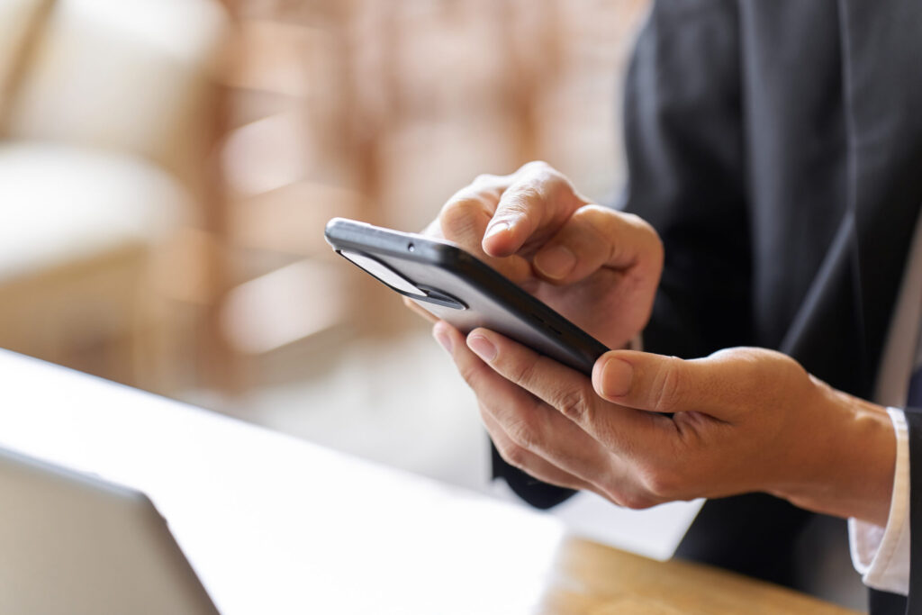 スマートフォンを操作しながら相談や問い合わせを行うビジネスパーソンの手元