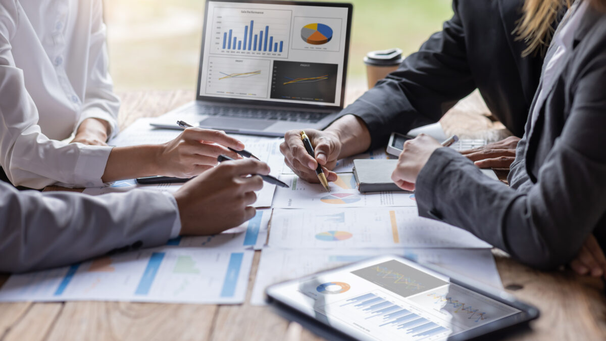マーケティング戦略を検討するビジネスチームが、グラフやデータ資料を基に打ち合わせをしている様子