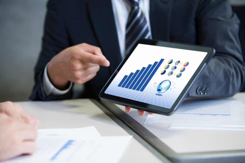 タブレット画面のグラフを見ながらホームページの改善について相談するビジネスパーソン